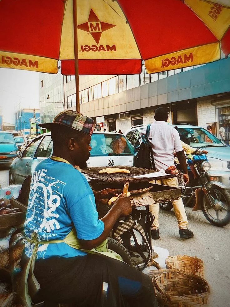 A street vendor working beside a busy commercial road